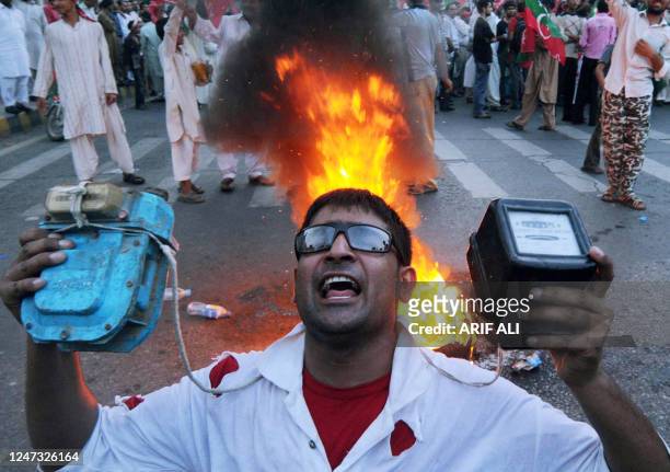 Supporter of Pakistani cricketer-turned-politician Imran Khan displays electricity and gas meters during a protest against an increase in petroleum...