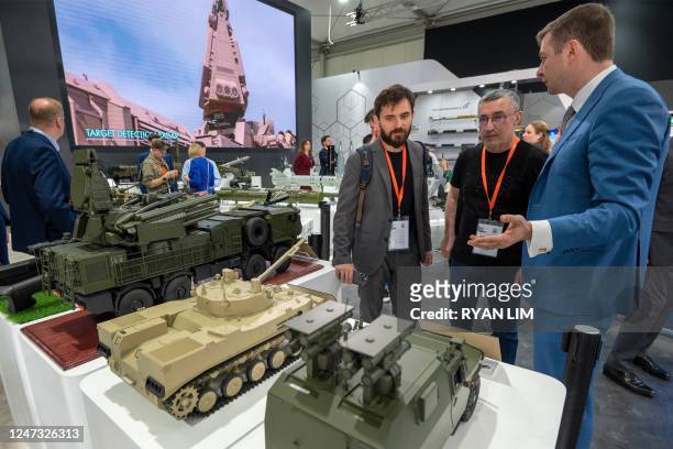 Visitors view mockups of ground vehicles as they tour the Russian pavilion during the International Defence Exhibtion at the Abu Dhabi International...