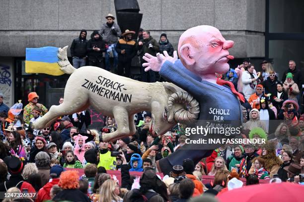 Revellers watch a float featuring German Chancellor Olaf Scholz being pushed by a buck with the name of Marie-Agnes Strack-Zimmermann , chairwoman of...
