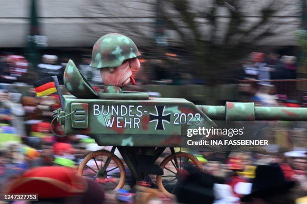 Revellers watch a float on the condition of the German armed forces Bundeswehr in 2023 during the Rose Monday street carnival parade in Duesseldorf,...