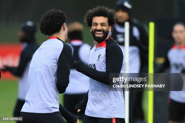 Liverpool's Egyptian striker Mohamed Salah shares a joke with Liverpool's English midfielder Curtis Jones during a team training session at the AXA...