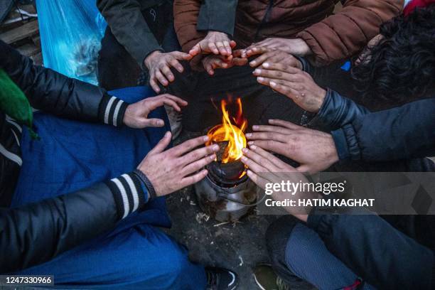 Illustration shows hands over a fire in front of a tent, part of the tents in front of the Petit Chateau - Klein Kasteeltje Fedasil Arrival center,...