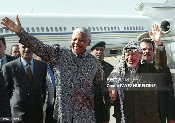 Palestinian Authority President Yasser Arafat and the former President of South Africa Nelson Mandela wave to a cheering crowd during their meeting...