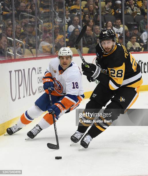 Marcus Pettersson of the Pittsburgh Penguins goes for a loose puck against Andy Andreoff of the New York Islanders in the first period during the...