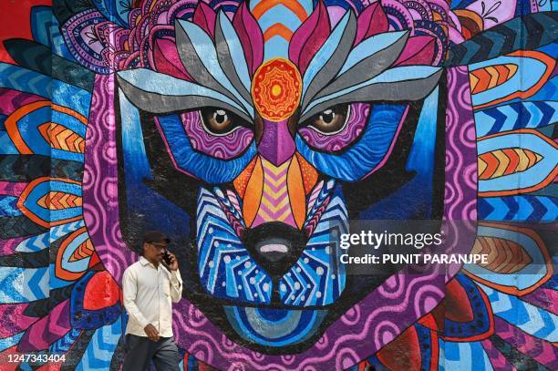 Man walks past a wall mural in Mumbai on February 21, 2023.