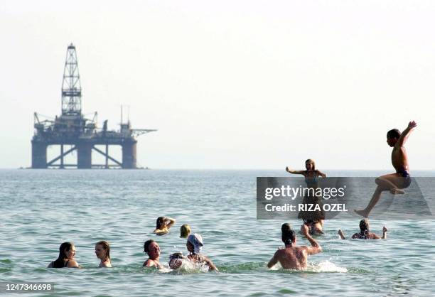 Azeri children cool off in Caspian Sea few kilometers away from an offshore oil rig 11 August 2003 close to where the new Baku-Tbilisi-Ceyhan oil...