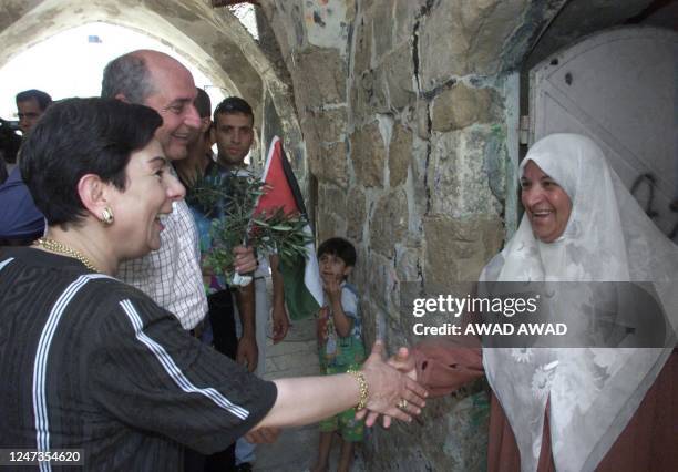 Palestinian spokeswoman Hanan Ashrawi shakes hands with a Palestinian women as Palestinian Authority official Faisal Husseini smiles during a tour of...