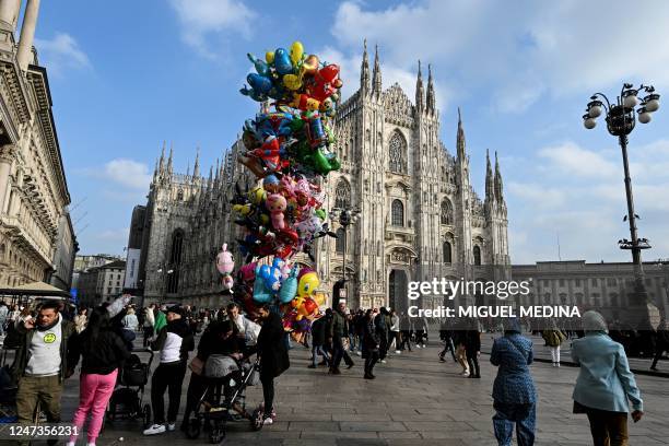 Pedestrians stroll in front of the Duomo di Milano on Duomo square, in central Milan, on February 21, 2023.