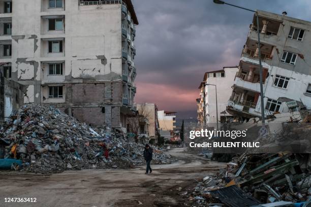 Man walks among collapsed buildings, a day after a 6.4-magnitude earthquake struck the region, in the coastal city of Samandag on February 21, 2023....