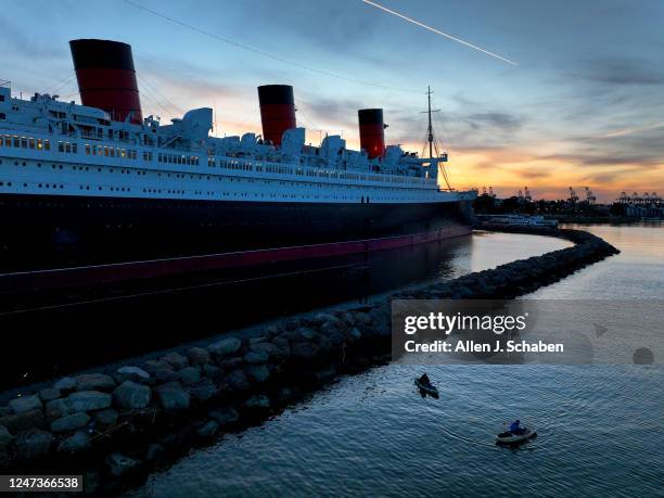 Long Beach, CA Amid cool weather, people fish from a kayaks with a view of the historic RMS Queen Mary ocean liner, that is 1,019.4 feet long and 181...