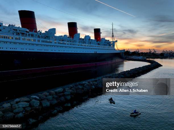 Long Beach, CA Amid cool weather, people fish from a kayaks with a view of the historic RMS Queen Mary ocean liner, that is 1,019.4 feet long and 181...