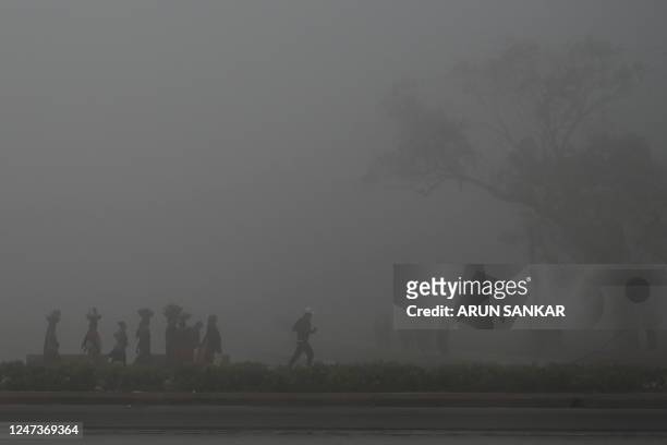 People walk along a road near India Gate amid heavy smog in New Delhi on February 22, 2023.