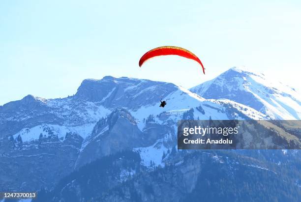 People enjoy paragliding during winter Interlaken district of Bern, Switzerland on February 22, 2023.