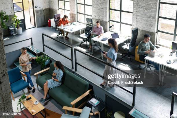 vista gran angular de una oficina de espacio abierto loft moderno con empresarios que trabajan en ella - coworking fotografías e imágenes de stock