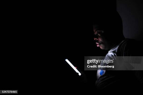 Resident browses a smartphone in a darkened residential building during a loadshedding power outage period, in Johannesburg, South Africa, on Monday,...