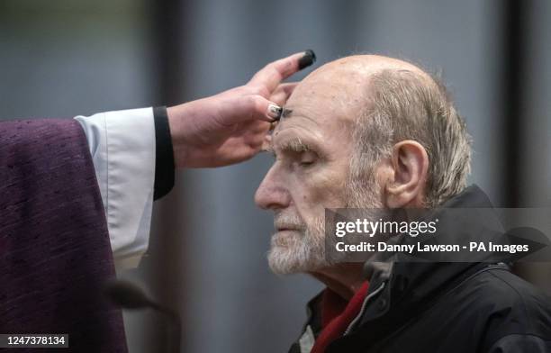 Canon Matthew Pollard makes an ash cross on the forehead of a member of the congregation during the imposition of the ashes during the Ash Wednesday...