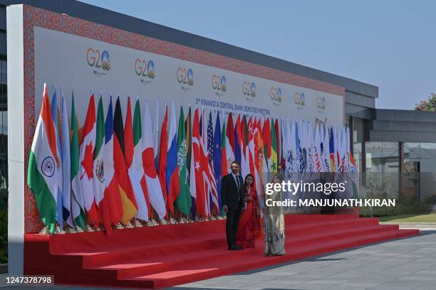 Officials stand near flags of participating countries and organisations erected at the Prestige Golfshire, the venue where the second meeting of the...
