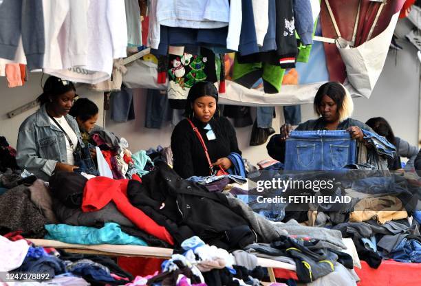 Sub-Saharan African women look for clothes in a thrift store in the market of Ariana, on the northern outskirts of Tunis on February 22, 2023. - A...