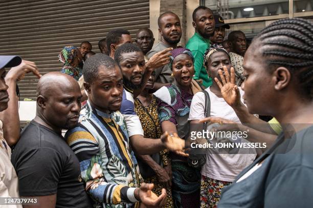 People shout at a bank worker outside a bank in Lagos on February 22, 2023. - Nigeria has been hit with a scarcity of cash after the central bank...