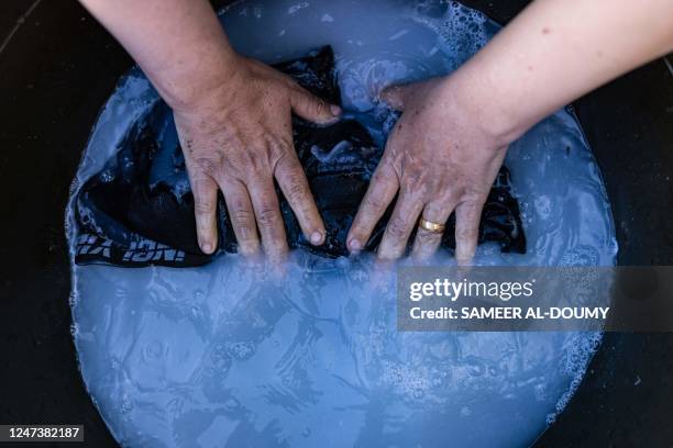 Turkish woman washes laundry in front of her tent in a makeshift camp next to the new Hatay stadium in Antakya, southern Turkey, on February 22,...