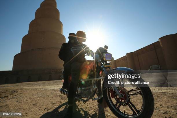 February 2023, Iraq, Samarra: A motorcyclist runs in front of the Spiral Malwiya Minaret, a mid-ninth century treasured Iraqi national monument....