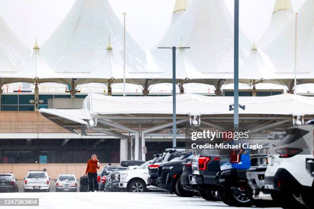 Woman walks to her car with her suitcases during a winter storm at Denver International Airport on February 22, 2023 in Denver, Colorado. More than...