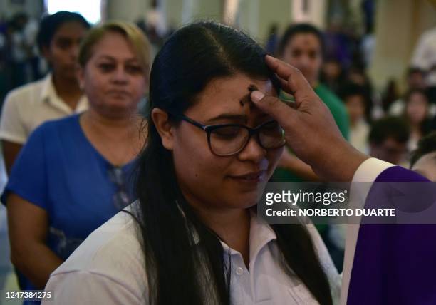 Priest marks with ashes the symbol of a cross on the forehead of a woman attending mass during the Catholic celebration of Ash Wednesday, at the...