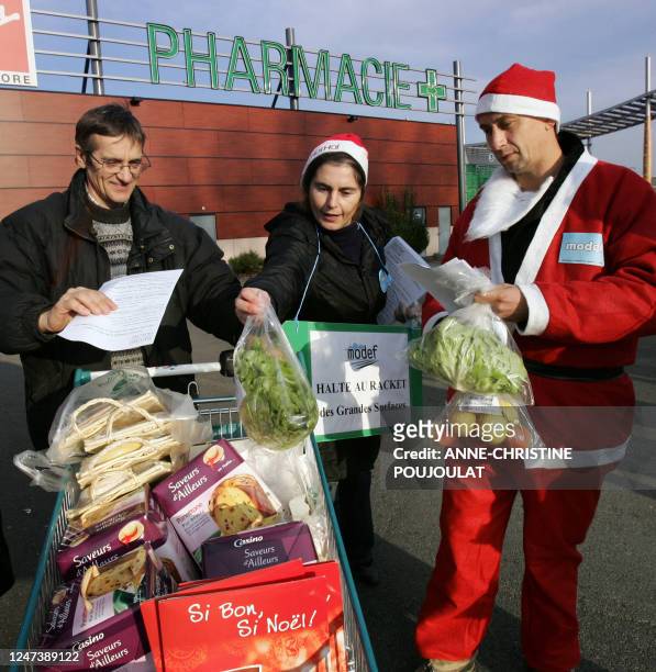 Des agriculteurs du Mouvement de défense des exploitants familiaux habillés en père Noël offrent des salades et des pommes à un consommateur, le 22...