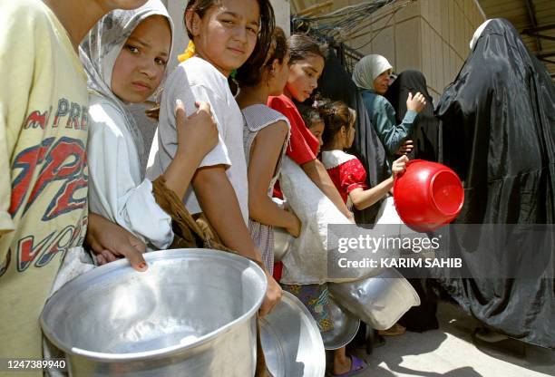 Underprivileged women and children form a queue for food at the Sunni Abdul Qader Al-Gaylani Mosque in central Baghdad after the midday Friday prayer...