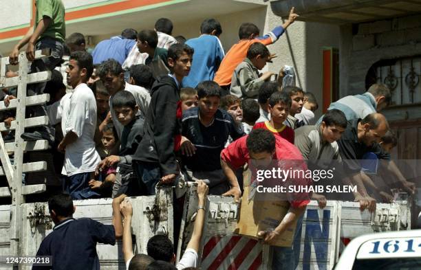 Palestinians jump on a United Nations truck to receive food aid after several days of Israeli closure of the Tel al-Sultan neighborhood in the...