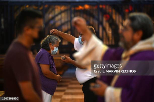 Priest sprinkles ash on the head of a woman attending mass during the celebration of Ash Wednesday at El Calvario parish in San Salvador, on February...