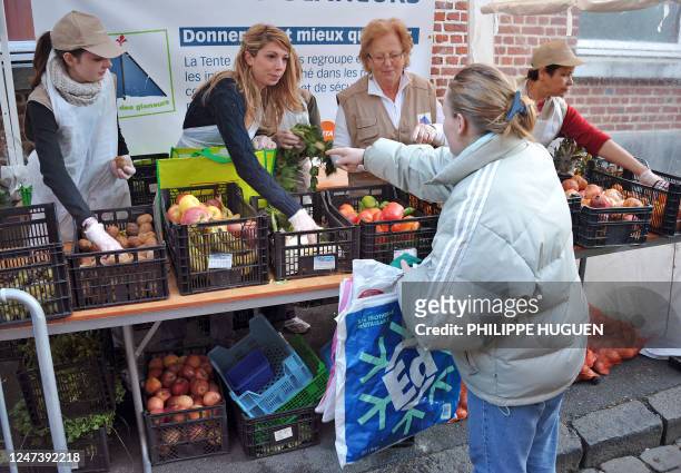 Une bénévole de l'association "La Tente des Glâneurs" distribue gratuitement un sac de fruits et légumes invendus à une femme, le 20 novembre 2011 à...