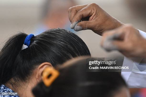 Priest sprinkles ash on the head of a woman attending mass during the celebration of Ash Wednesday at El Calvario parish in San Salvador, on February...