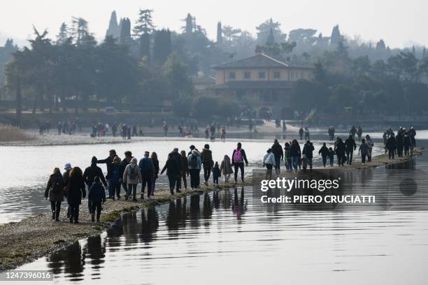 People walk from the small island of San Biagio, off Manerba del Garda, Lake Garda, towards the Belvedere point on February 21 where the water level...