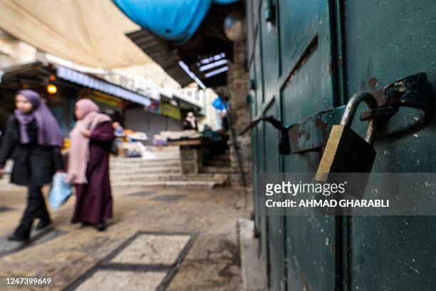 Palestinians walk past closed shops during a general strike in the Old City of Jerusalem on February 23, 2023. - The Israeli army and Palestinian...