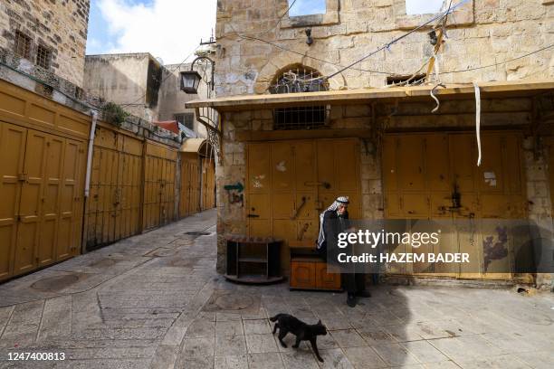 Man sits in front of a closed shop in a market area in the occupied West Bank city of Hebron on February 23 during a general strike called to protest...