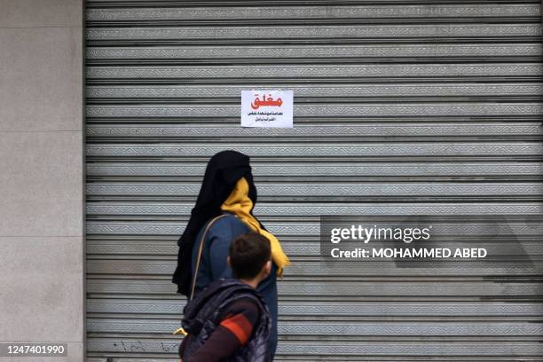 People walk past closed shops in Gaza City on February 23, 2023 during a general strike called to protest against the Israeli army raid in Nablus the...