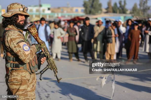 Taliban security personnel stand guard as Afghan people wait to cross into Pakistan, near the closed Torkham gate at the Torkham border crossing...