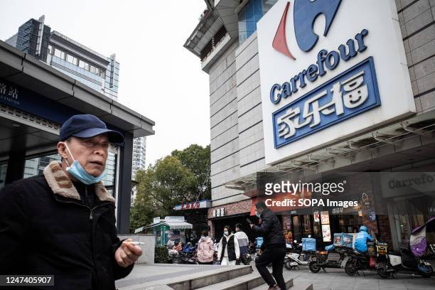 People walk past a giant signboard of Carrefour store in Wuhan. Carrefour entered the Chinese market in the year 1995 and expanded very quickly,...
