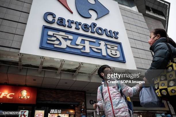 Boy and a woman walk past a giant signboard of Carrefour store in Wuhan. Carrefour entered the Chinese market in the year 1995 and expanded very...