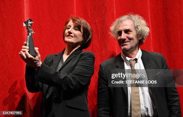 French cinematographer Caroline Champetier stands next to French director Philippe Garrel and holds her "Berlinale Camera" award she was given during...