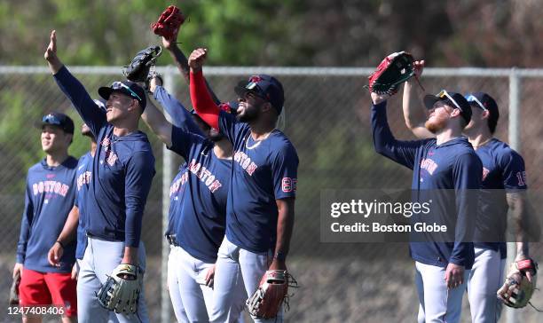 Fort Myers, FL Boston Red Sox outfielders use their hands and gloves to block the sun during a fielding drill.
