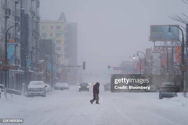 Pedestrian crosses a snow covered road during a storm in Minneapolis, Minnesota, US, on Thursday, Feb. 23, 2023. A sprawling winter storm is sweeping...