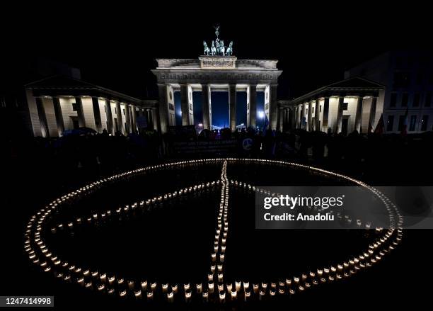 Peace sign is formed with candles in front of the Brandenburg in Berlin marking the first anniversary of the war between Russia and Ukraine, Berlin,...