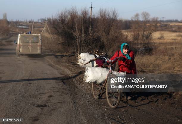 An elderly woman pushes her bicycle loaded with hay and brushwood on a roadside near village of Kolisnykivka, in the Kharkiv region on February 23...