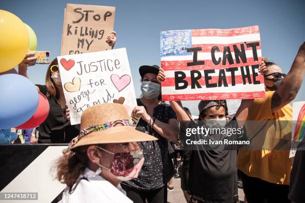 Boy holding a sign saying "I can't breathe" on the background of an American flag during the anti-racist protest organized in memory of George Floyd...