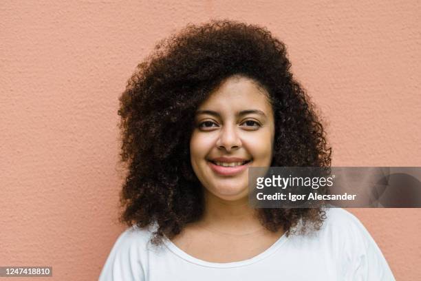 curly hair woman on coral wall - hefty brand name imagens e fotografias de stock