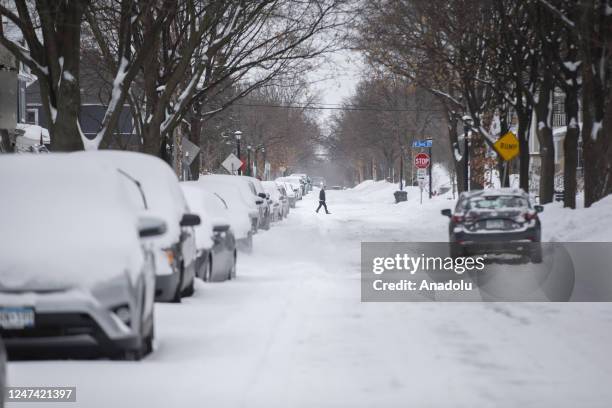 Man walks across the street in Minneapolis as a sprawling winter storm sweeps across the northern United States and winter storm warnings are up for...