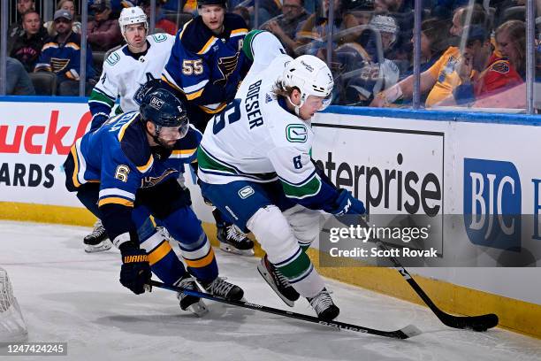 Marco Scandella of the St. Louis Blues defends against Brock Boeser of the Vancouver Canucks at the Enterprise Center on February 23, 2023 in St....