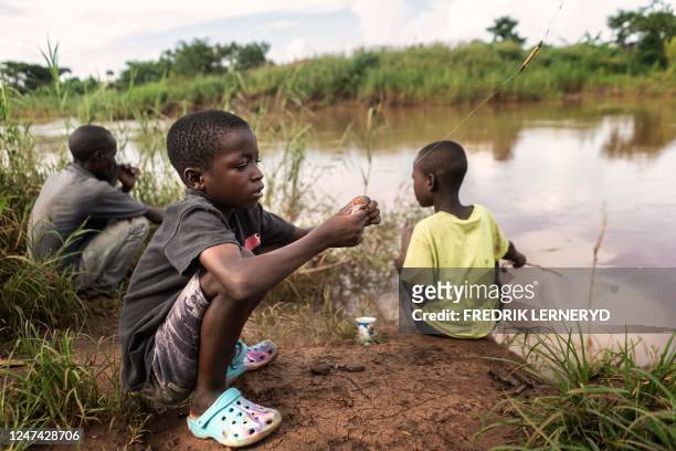 Two boys and a man fish in a river in Mtandile in Lilongwe, on February 20, 2023 in an area that has been highly affected by the cholera outbreak due...